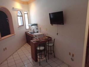 a kitchen with a bar and a television on the wall at Departamentos cerca del malecón, a unos pasos del estadio de Béisbol in Mazatlán