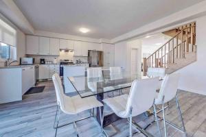 a dining room with a glass table and white chairs at NEWLY BUILT LUXURIOUS 3BRM TOWN HS/AIRPORT/PARKING in Brampton