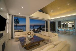 un soggiorno con divani e un tavolo in una camera di Villa Nirvana - Beachfront Tropical Chic 4BR Haven in Cape Panwa, Phuket a Ban Ao Makham