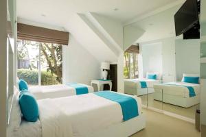 una camera da letto bianca con due letti e una televisione di Villa Nirvana - Beachfront Tropical Chic 4BR Haven in Cape Panwa, Phuket a Ban Ao Makham Altre 25 foto