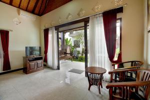 uma sala de estar com uma televisão e uma mesa e cadeiras em Queen Bisma Villa - 10 min walking to Ubud Center em Ubud