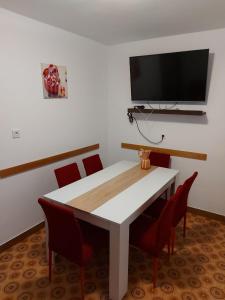 einen Esstisch mit roten Stühlen und einen Flachbild-TV in der Unterkunft Apartment Bila - 15m from the sea in Tisno