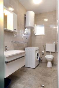 uma casa de banho com um WC, um lavatório e uma máquina de lavar roupa em Apartments Ante - 50 M from the sea em Seget Vranjica