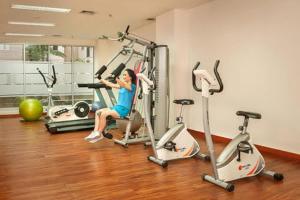 a woman sitting on a treadmill in a gym at Cottonwood Apartment at Sudirman Suites Bandung 5-pax in Bandung