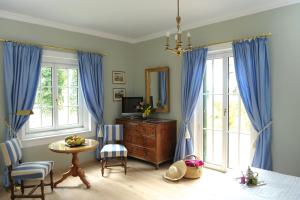 Schlafzimmer mit blauen Vorhängen, einem Tisch und einem Spiegel in der Unterkunft Hotel Schloss Leonstain in Pörtschach am Wörthersee