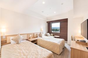 a hotel room with two beds and a flat screen tv at UNIZO INN Kanazawa Hyakumangoku Dori in Kanazawa