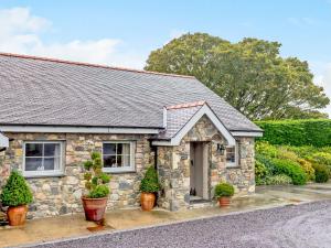 una casa in pietra con piante in vaso di fronte di Beudy - Uk31388 a Caeathro