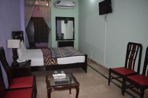 um quarto com uma cama, uma cadeira e uma mesa em Hotel The Oriel Islamabad em Islamabad