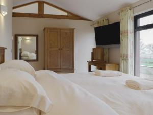 a bedroom with a bed with white sheets and a tv at Castle Farm - Uk10563 in Henrys Moat