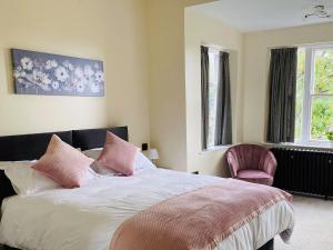 Un dormitorio con una cama con almohadas rosas y una silla en Heath View, en Cheddleton