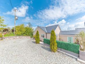 a house with a gravel driveway and bushes at The Lodge in Dalton in Furness