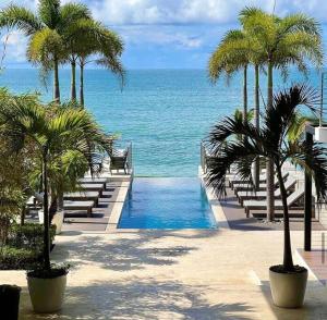 um resort com piscina, palmeiras e oceano em Charming Zen-style Beach apartment at Punta Caelo em San Carlos