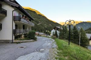 a street in front of a building with people on a balcony at Cambrembo a 3km da foppolo casa x6persone con Camino e Wifi in Valleve