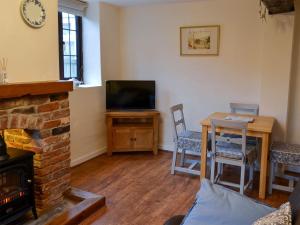 a living room with a fireplace and a table and a television at Ikkle Cottage in Blidworth