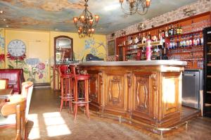 a bar with a wooden counter and red stools at Hôtel Restaurant La Belle Epoque in Le Creusot