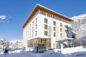 budynek w śniegu przed górą w obiekcie Hotel Allegra 3 Stern Superior w mieście Pontresina