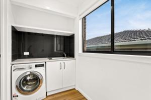 uma lavandaria com uma máquina de lavar roupa e uma janela em Cape View San Remo em San Remo