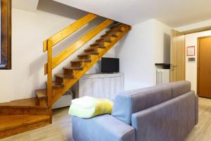 ein Wohnzimmer mit einem Sofa und einer Treppe in der Unterkunft Cambrembo a 3km da foppolo casa x6persone con Camino e Wifi in Valleve