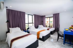 um quarto de hotel com três camas e uma secretária em The Rabbit Hole Hotel & SPA em Siem Reap