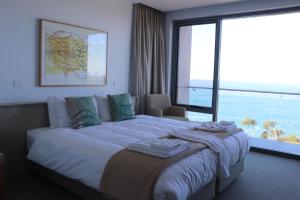 a bedroom with a large bed with a large window at Tathra Hotel & Motel in Tathra