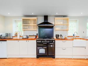 a kitchen with a stove and a tv in it at Coachmans Cottage - Uk11449 in Mellis