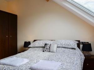 um quarto com uma cama com duas almofadas e uma janela em Ghillie Cottage em Cockermouth