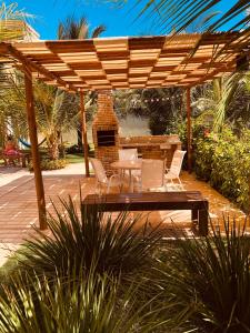 un patio con mesa y sillas bajo una pérgola de madera en Exelente Apartamento Porto das Dunas, en Aquiraz
