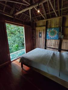um quarto com uma cama e uma grande janela em Canjahawon Nipa Hut Homestay em Siquijor