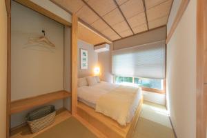 a small bedroom with a bed and a window at YAMO-Izukogen in Yawatano