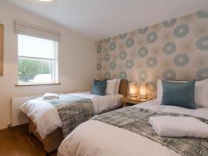 a bedroom with two beds and a window at Coot Lodge in Somerford Keynes