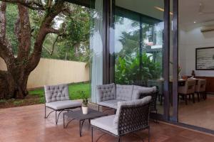 a patio with chairs and a table and a tree at StayVista Bella Antlia 3BHK, with Pvt Pool & Paddy view- Parra, North Goa in Anjuna