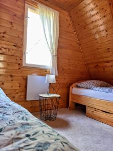 um quarto com uma cama e uma janela num chalé de madeira em The WoodHouse Vendégház em Nagymaros