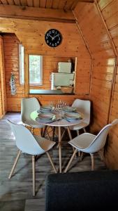 uma sala de jantar com mesa e cadeiras e um relógio em The WoodHouse Vendégház em Nagymaros