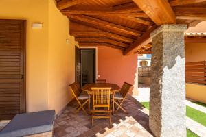 eine Terrasse mit einem Tisch und Stühlen unter einer Holzdecke in der Unterkunft Villa Max in Villasimius