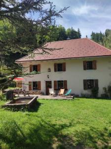 uma grande casa branca com um quintal com cadeiras em chalet Saint Joseph au coeur du massif de la Chartreuse ! em Saint-Christophe-sur-Guiers