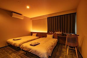 a hotel room with two beds and a window at CURIO Shirakawago in Shirakawa