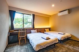 Duas camas num quarto com uma secretária e uma janela em CURIO Shirakawago em Shirakawa