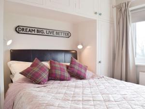 ein Bett mit zwei Kissen und ein Schild an der Wand in der Unterkunft The Hays in Burton