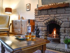 a living room with a stone fireplace and a table with glasses at Haagwood Cottage in Cretshengan