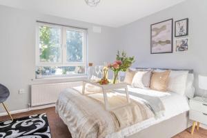 Un dormitorio con una cama y una mesa con flores. en LiveStay-4 Bed London Townhouse, Private Terrace, Parking, en Brentford
