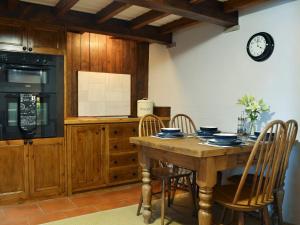 cocina con mesa con sillas y reloj en la pared en Courtyard Cottage At Dam Hall Barn, en Peak Forest