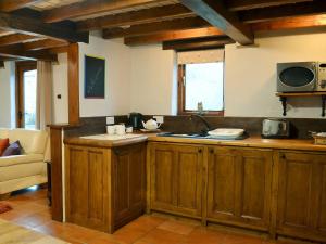 cocina con armarios de madera y encimera en Courtyard Cottage At Dam Hall Barn, en Peak Forest