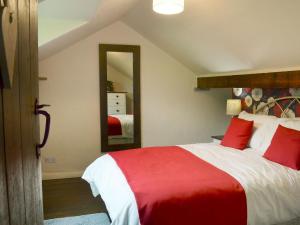Un dormitorio con una cama roja y blanca y un espejo en Courtyard Cottage At Dam Hall Barn, en Peak Forest
