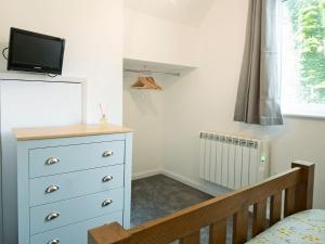 a bedroom with a blue dresser and a crib at Coley Cottage in Wainfleet All Saints