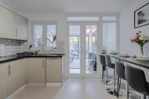 una cocina con armarios blancos y una mesa con sillas. en LiveStay-4 Bed London Townhouse, Private Terrace, Parking, en Brentford