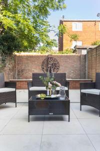 une terrasse avec des chaises et une table fleurie. dans l'établissement LiveStay-4 Bed London Townhouse, Private Terrace, Parking, à Brentford
