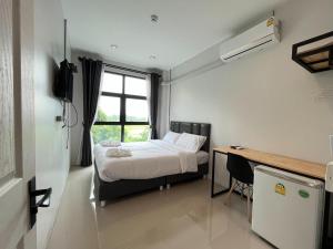 a bedroom with a bed and a desk and a window at Life Hotel Rong Khun in Ban Mai