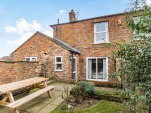 a brick cottage with a wooden bench in front of it at West End Farm Lodge in Burton Agnes