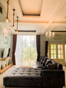 a living room with a large couch in front of a window at Villa Kamar Tamu Warungboto in Timuran