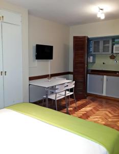 Habitación con cama, mesa y TV. en Studio Maipu en Buenos Aires